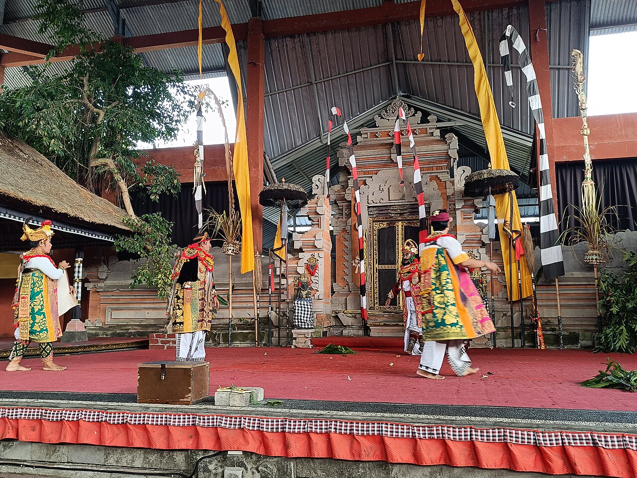 TĂ€nzer in traditionellen KostĂŒmen bei einer Barong-Tanz-AuffĂŒhrung vor einem balinesischen Tempel