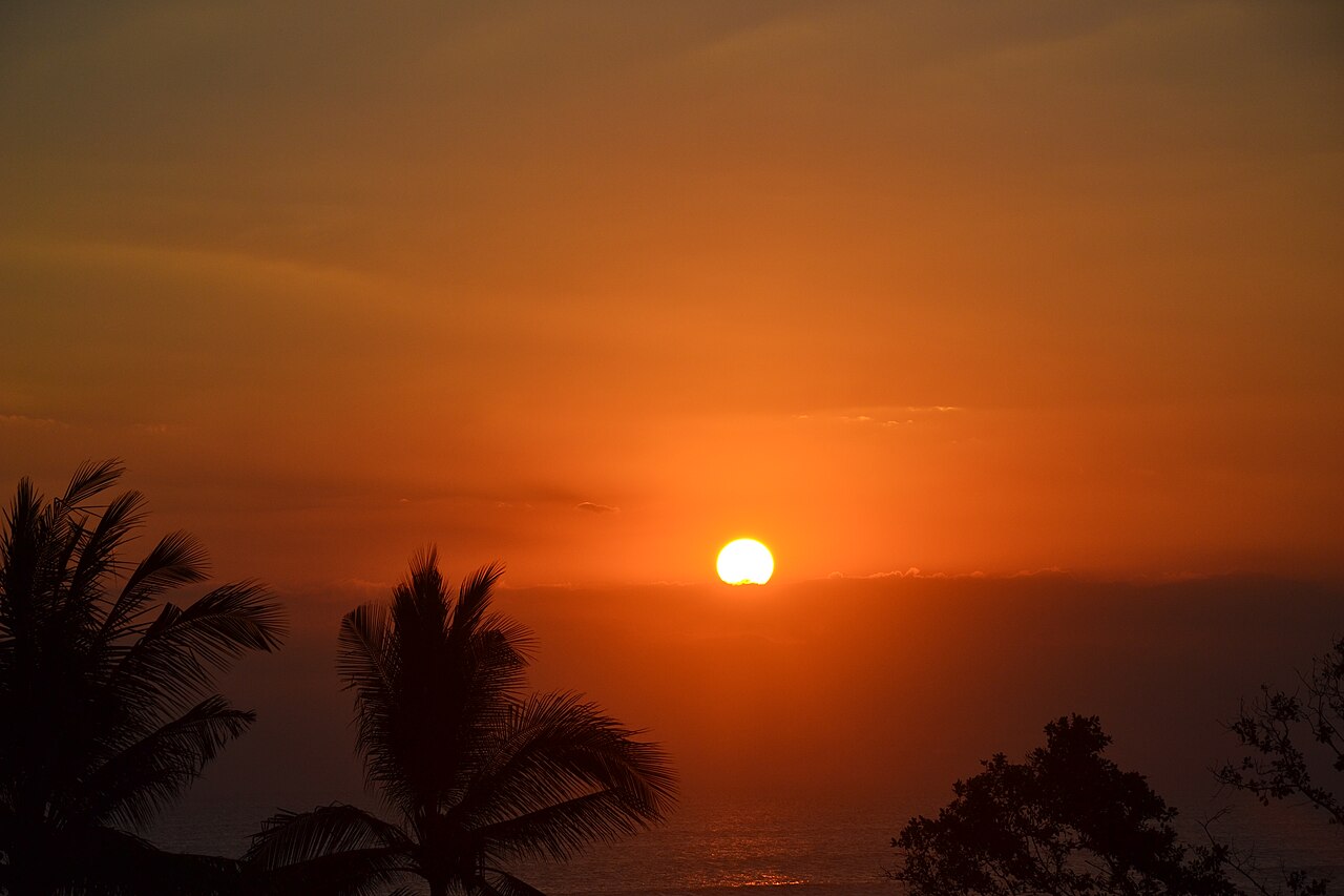 Sonnenuntergang mit Palmensilhouetten über dem Meer bei Seminyak auf Bali
