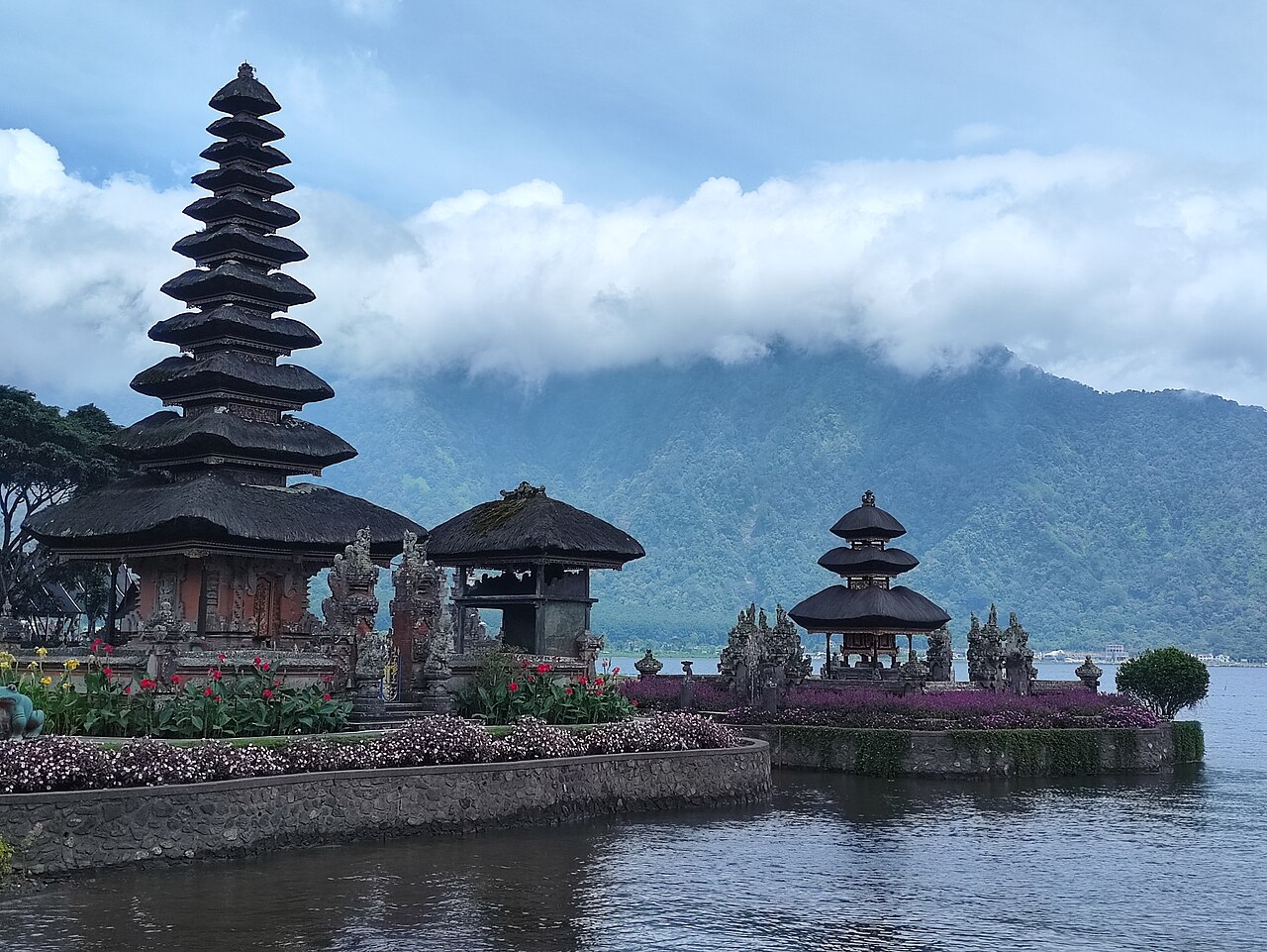 Mehrstöckige Meru-Türme des Pura Ulun Danu Bratan am Ufer des Bratansees vor bewaldetem Vulkanhang