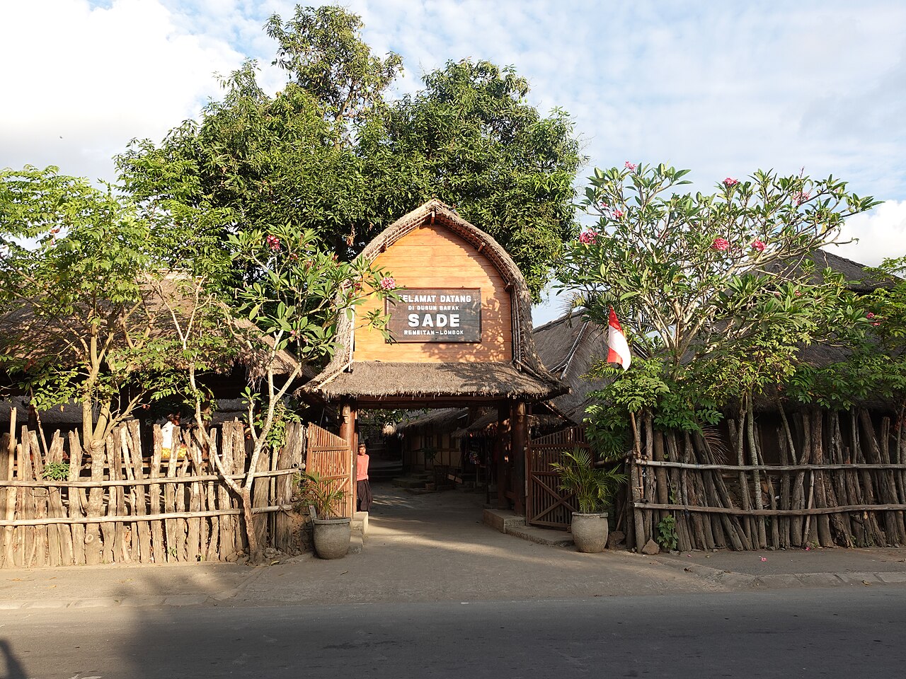Eingangstor mit Schild und Reetdächern im traditionellen Sasak-Dorf Sade auf Lombok
