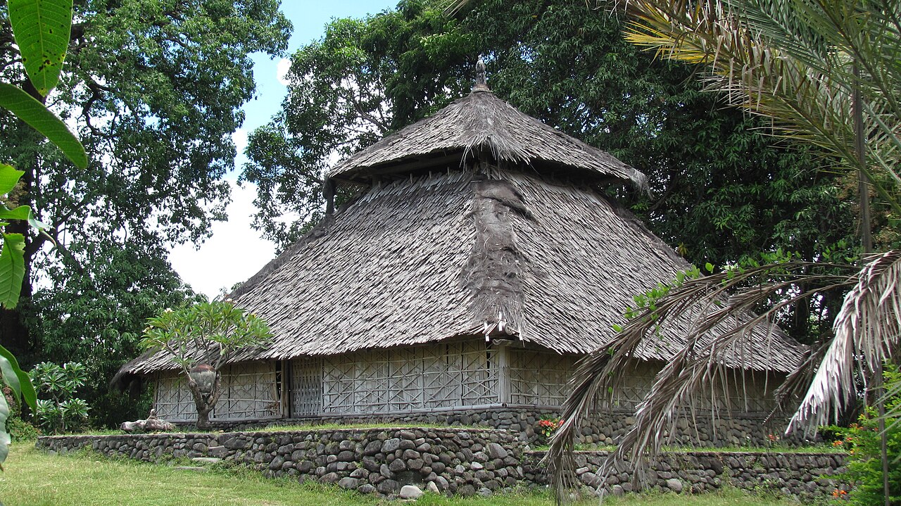 Historische Moschee Bayan Beleq auf Lombok: Bau mit steilem, gestuftem Dach auf einem Steinsockel zwischen Bäumen