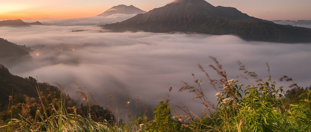 Nebel über einem Tal bei Pinggan auf Bali in der Morgendämmerung mit zwei Vulkanbergen im Hintergrund