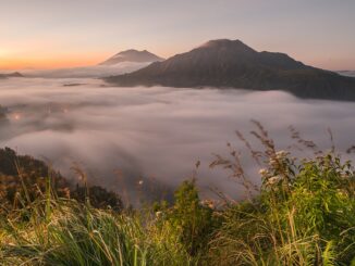 Nebel über einem Tal bei Pinggan auf Bali in der Morgendämmerung mit zwei Vulkanbergen im Hintergrund