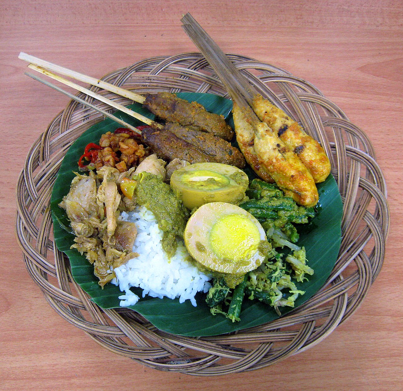 Korb mit Bananenblatt, Reis, zwei Sorten Sate Lilit, Ei, Hähnchen und Gemüse